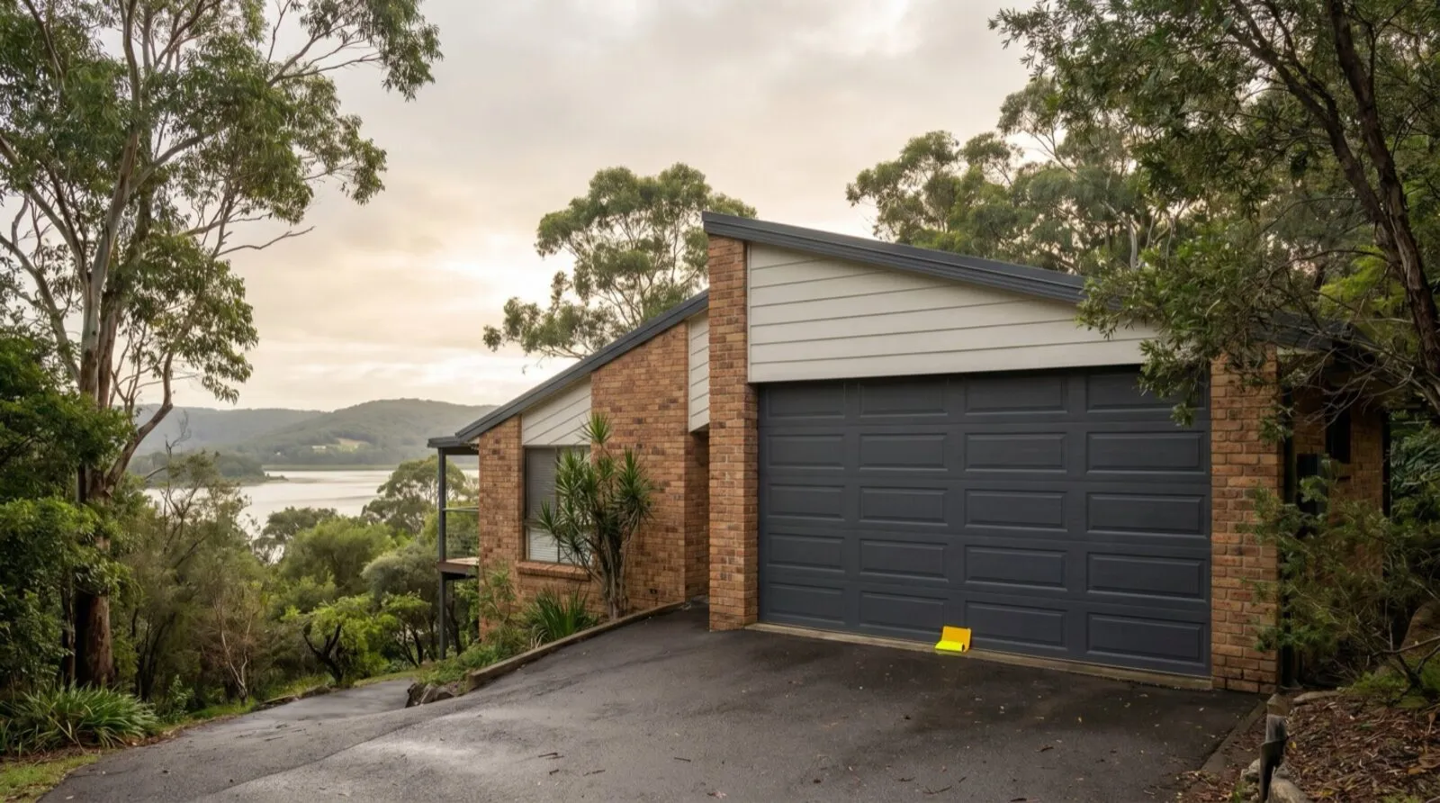 A double sectional garage door on a hillside home at Wyoming, with bushland and Brisbane Water beyond